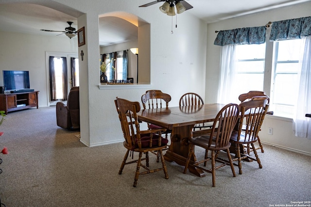 dining space with arched walkways, carpet, a ceiling fan, and baseboards