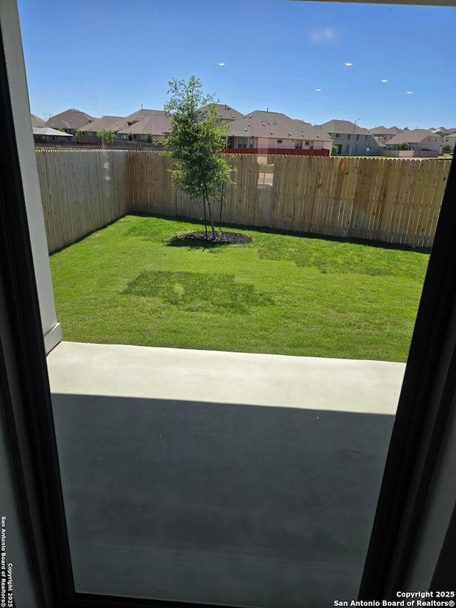 view of yard featuring a residential view, a patio area, and a fenced backyard