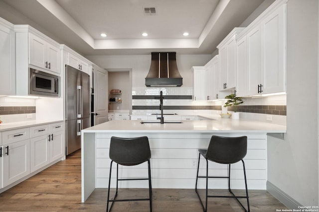 5219 Breeze Way, San Antonio, TX 78249 - kitchen with premium range hood, appliances with stainless steel finishes, a sink, a kitchen breakfast bar, and white cabinetry