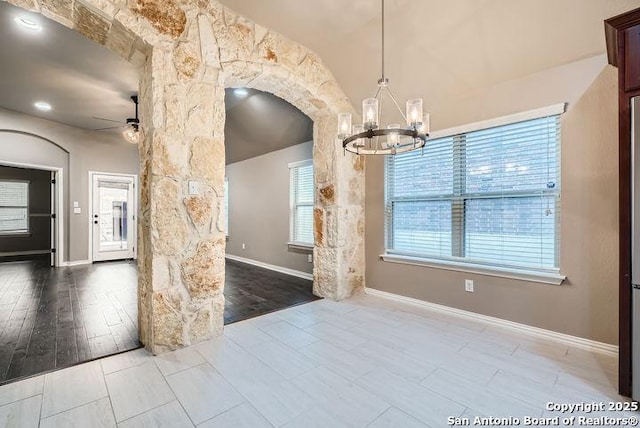 spare room with baseboards, arched walkways, wood finished floors, and ceiling fan with notable chandelier