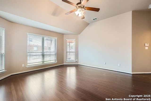 empty room featuring lofted ceiling, baseboards, visible vents, and dark wood-style flooring