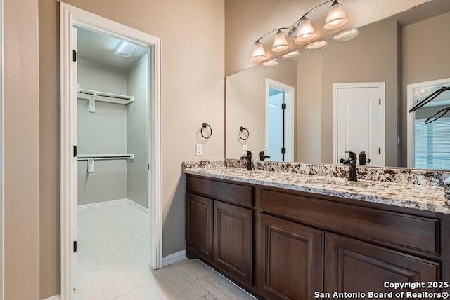 full bath with a walk in closet, a sink, and double vanity