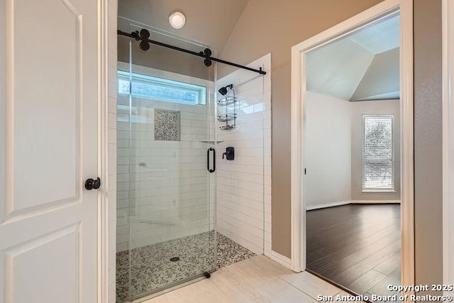 full bathroom featuring lofted ceiling, a shower stall, and wood finished floors