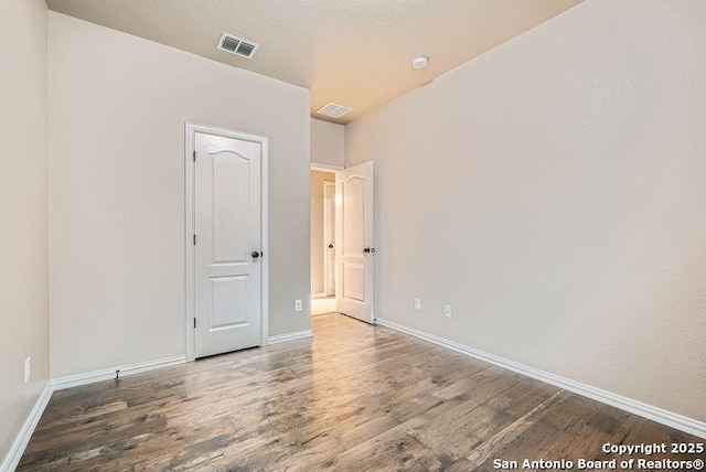 unfurnished room featuring visible vents, baseboards, and wood finished floors