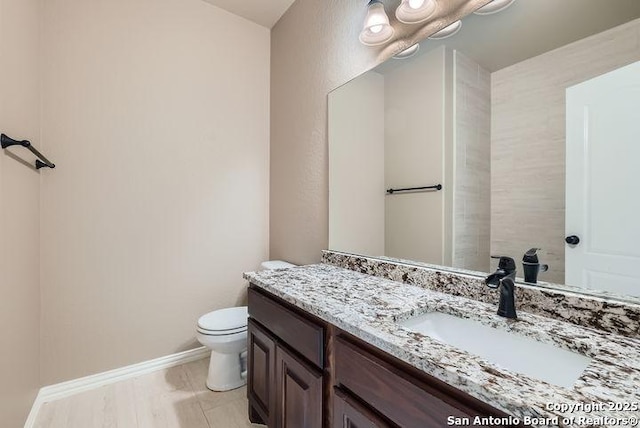 bathroom featuring baseboards, vanity, toilet, and wood finished floors