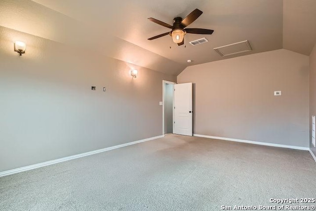 carpeted spare room with attic access, visible vents, vaulted ceiling, and baseboards