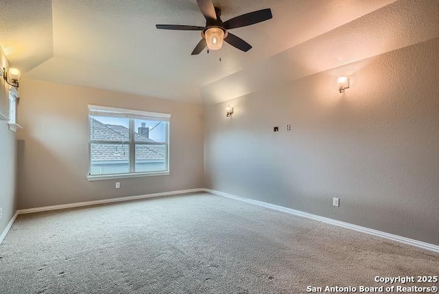 carpeted empty room featuring lofted ceiling, baseboards, and a ceiling fan