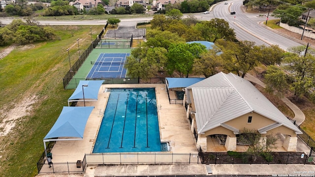 view of swimming pool featuring a tennis court and fence