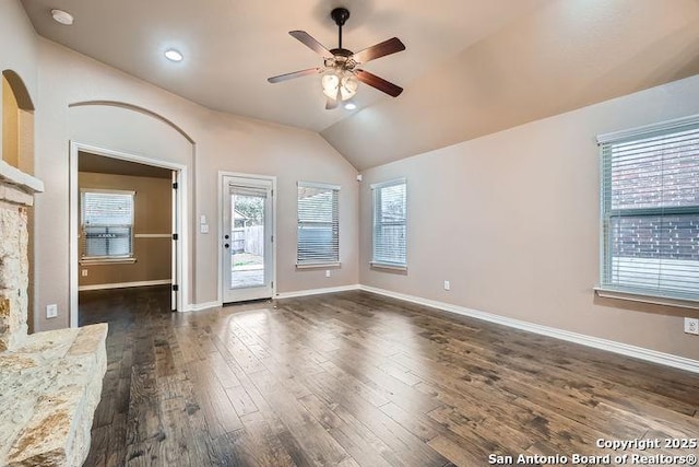 interior space with lofted ceiling, dark wood-style floors, a ceiling fan, and baseboards