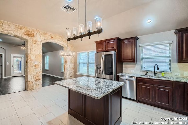 kitchen featuring visible vents, arched walkways, stainless steel appliances, pendant lighting, and a sink