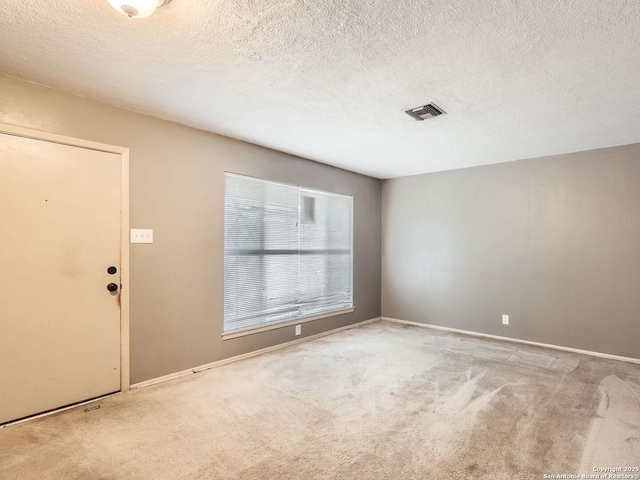 spare room with light carpet, a textured ceiling, and visible vents