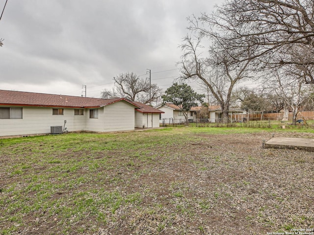 view of yard with central AC and fence