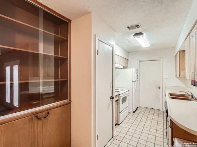 kitchen with white appliances, light tile patterned floors, visible vents, light countertops, and a sink