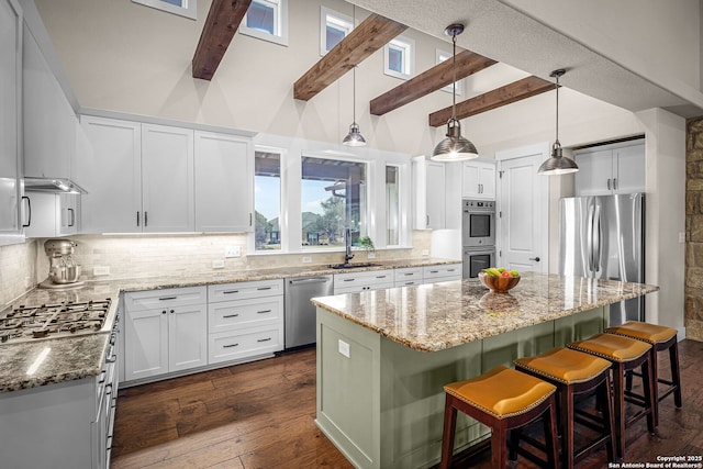 kitchen with white cabinets, a center island, stainless steel appliances, stone counters, and a kitchen bar