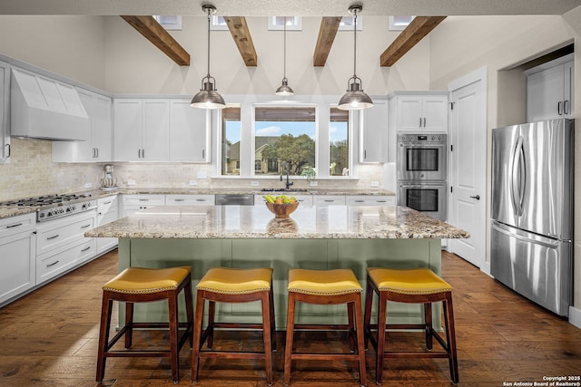 kitchen featuring a sink, stainless steel appliances, a kitchen island, and a kitchen breakfast bar