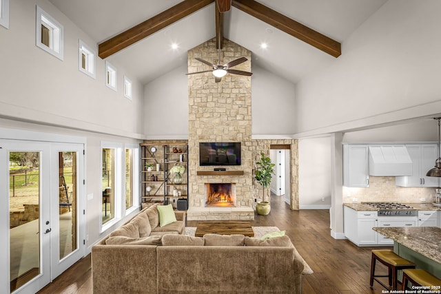 living room with dark wood finished floors, a stone fireplace, and beamed ceiling