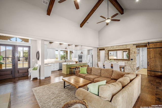 living area featuring high vaulted ceiling, a barn door, visible vents, and dark wood-style flooring