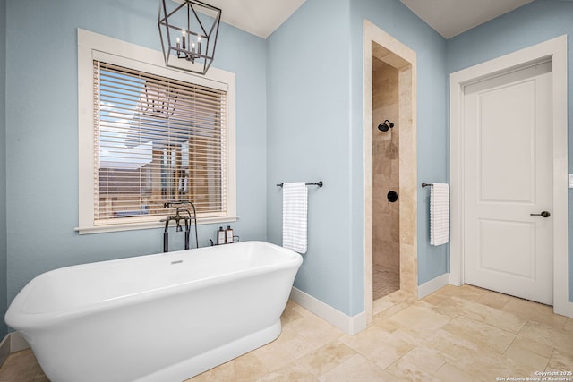 full bathroom with a freestanding bath, an inviting chandelier, a shower stall, and baseboards