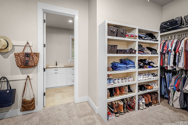 walk in closet with a sink and light colored carpet