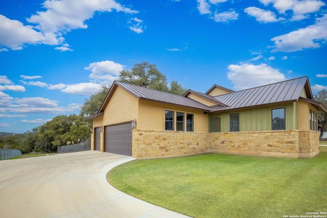 ranch-style home featuring an attached garage, a front yard, a standing seam roof, metal roof, and stone siding