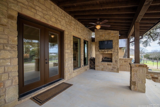 view of patio featuring ceiling fan, french doors, and an outdoor stone fireplace