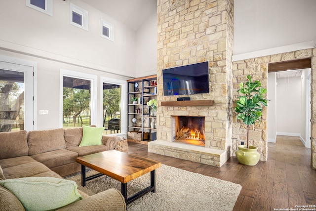 living room featuring high vaulted ceiling, dark wood finished floors, and a stone fireplace