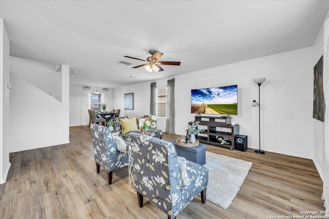 living area featuring baseboards, wood finished floors, visible vents, and a ceiling fan