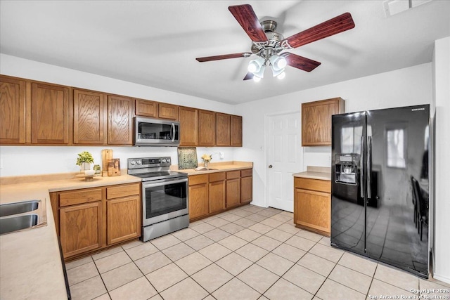 kitchen with light tile patterned floors, stainless steel appliances, visible vents, light countertops, and brown cabinets