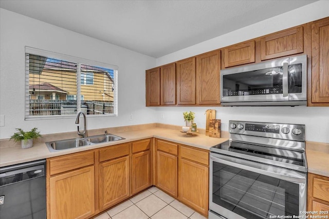 kitchen featuring stainless steel appliances, brown cabinets, light countertops, and a sink