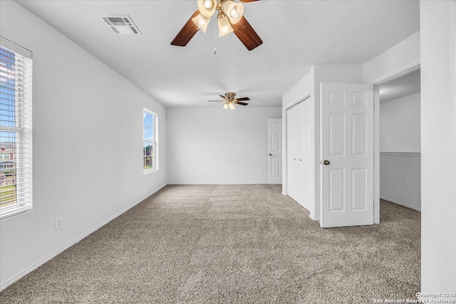 carpeted empty room featuring ceiling fan and visible vents