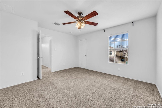 carpeted empty room with a ceiling fan, visible vents, and baseboards