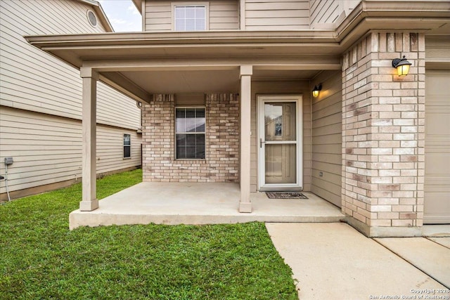 entrance to property featuring a garage, covered porch, and brick siding