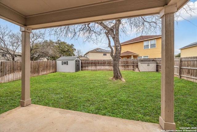 view of yard with a fenced backyard, a storage unit, a patio, and an outbuilding