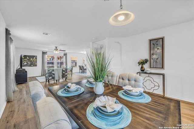 dining room featuring visible vents, ceiling fan, baseboards, and wood finished floors