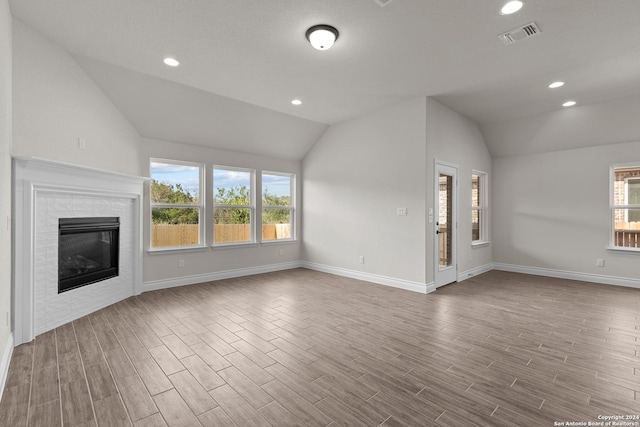 unfurnished living room with vaulted ceiling, a fireplace, wood finished floors, and recessed lighting