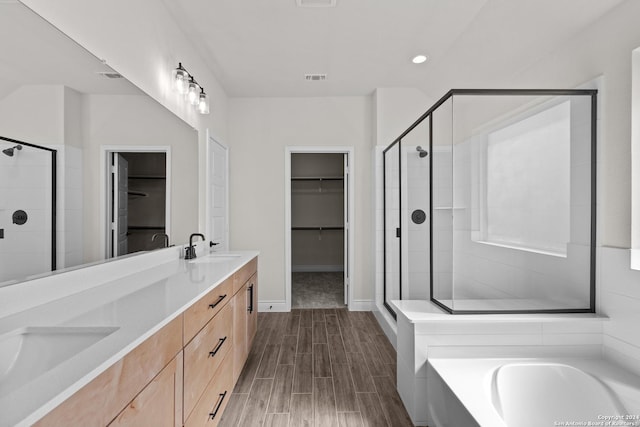 full bathroom with double vanity, visible vents, a walk in closet, a shower stall, and a sink