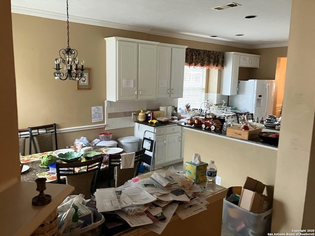 kitchen with visible vents, white cabinets, hanging light fixtures, white fridge with ice dispenser, and crown molding