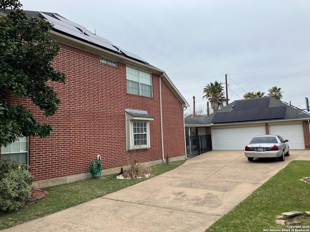 view of side of property with a garage, solar panels, and brick siding