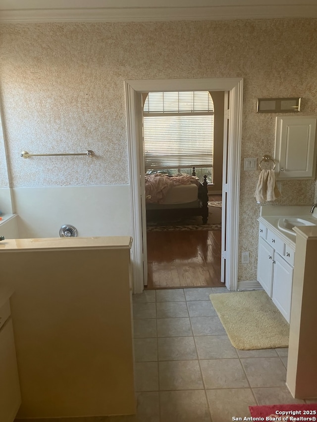 full bathroom featuring vanity, tile patterned floors, wallpapered walls, ensuite bath, and crown molding