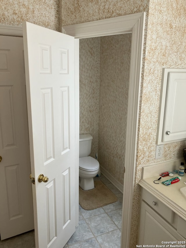 bathroom featuring tile patterned floors, toilet, and wallpapered walls