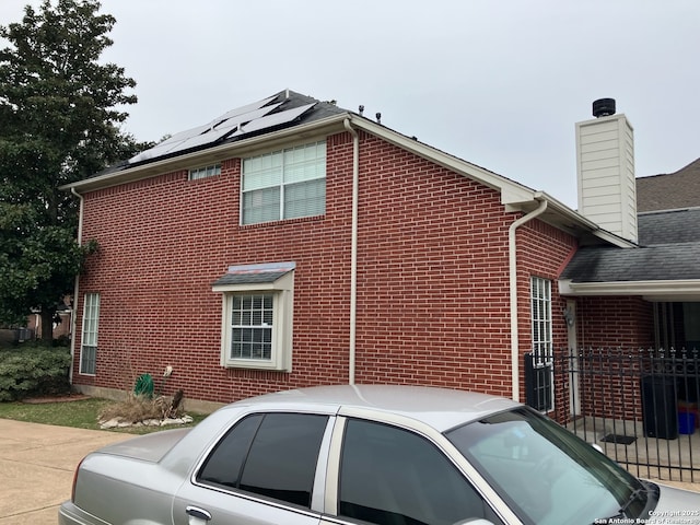 view of side of home with roof mounted solar panels and brick siding