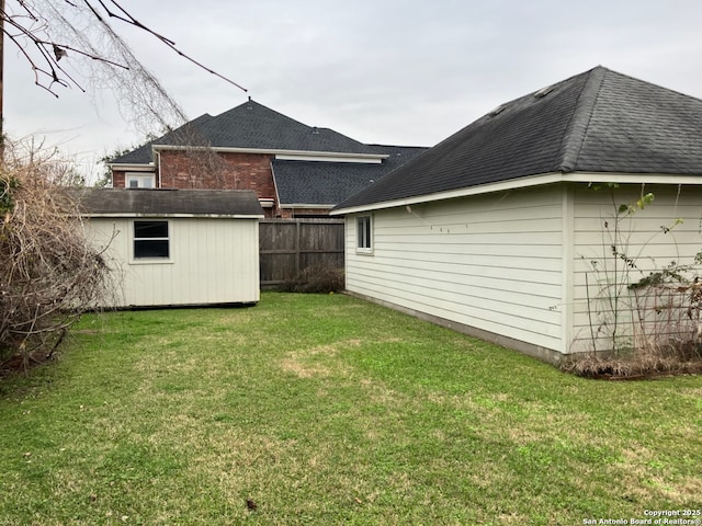 view of yard featuring a shed, fence, and an outbuilding