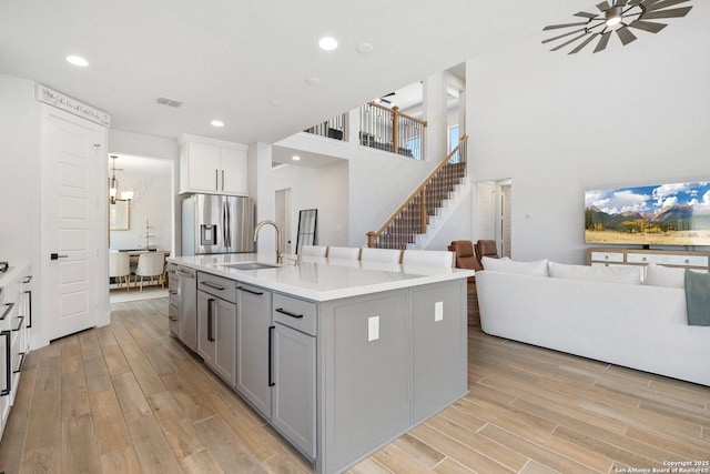 kitchen featuring gray cabinetry, light wood-style flooring, a sink, open floor plan, and stainless steel appliances