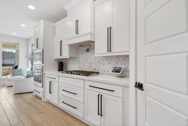 kitchen with tasteful backsplash, light wood-type flooring, recessed lighting, appliances with stainless steel finishes, and white cabinetry