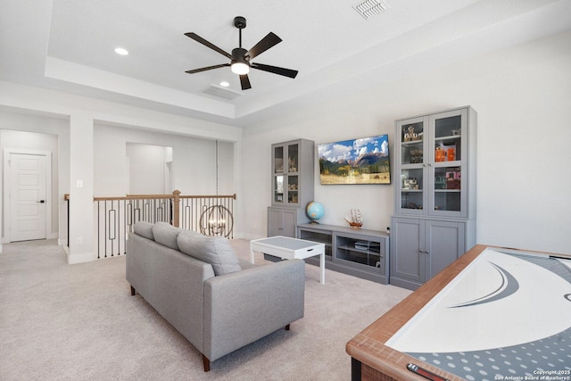 living room featuring a tray ceiling, visible vents, light carpet, and recessed lighting