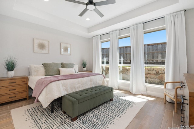 bedroom featuring light wood finished floors, recessed lighting, a raised ceiling, and a ceiling fan