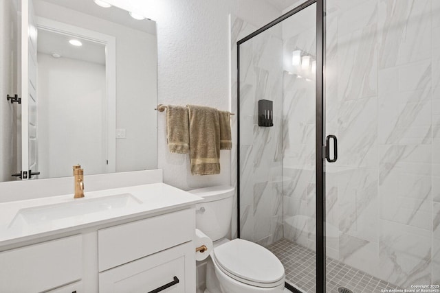 full bathroom with a marble finish shower, toilet, vanity, and a textured wall