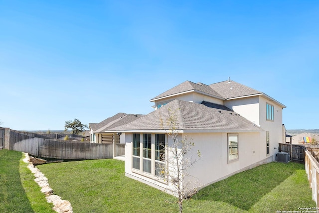 back of house featuring central air condition unit, stucco siding, a lawn, a fenced backyard, and roof with shingles