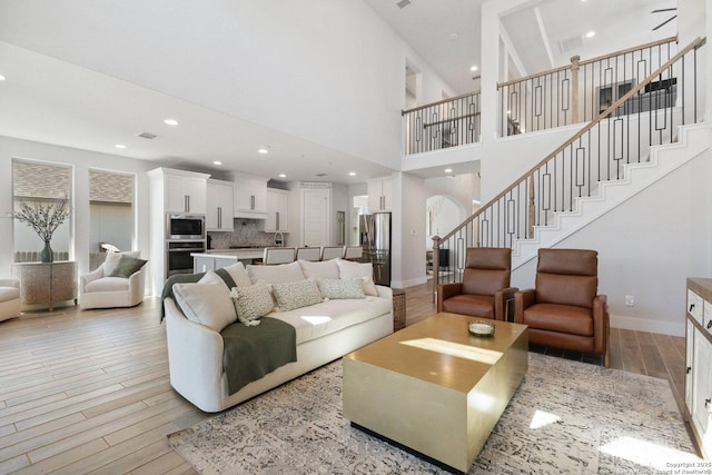 living area featuring recessed lighting, baseboards, stairs, and light wood finished floors