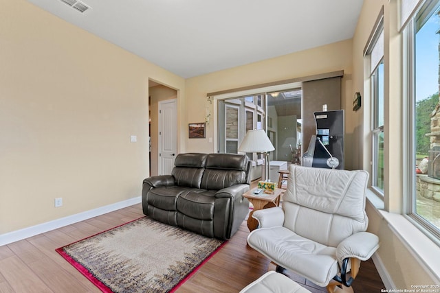 living area with a healthy amount of sunlight, visible vents, baseboards, and wood finished floors